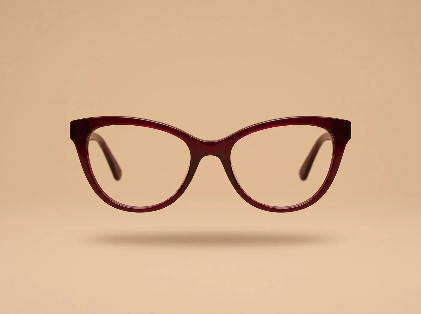 Occhiali cat-eye bordeaux su fondo sabbia